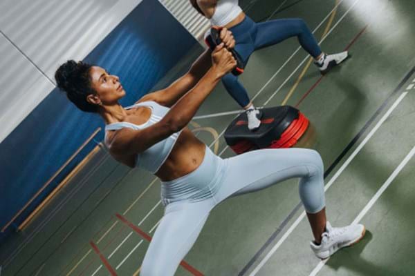 A female les mills instructor practicing les mills bodystep with a les mills smart step and a les mills weight plate